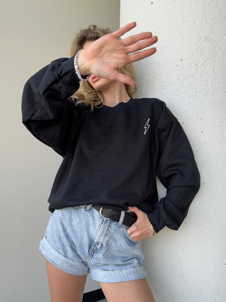 Model wearing The Incredible Sweatshirt, holding her hand up and showcasing front lightning bolt details.