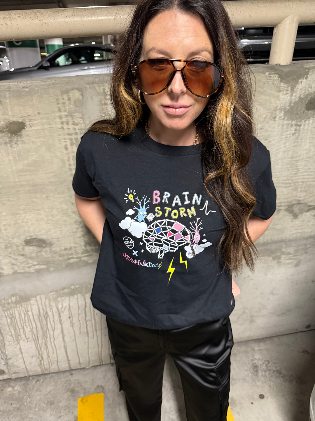 Model wearing the Ladyspinedoc x The Neuron Family brain storm / brainstorm short sleeve tee shirt in black.