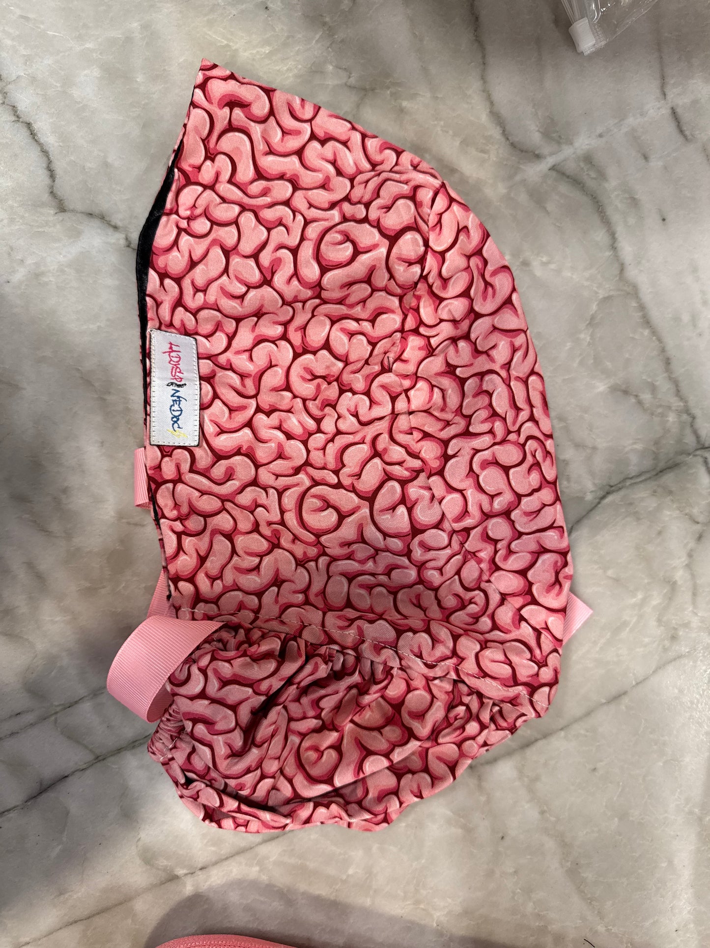 Flat lay of the Cortex Cap - Pink Scrub Hat with Brain Design