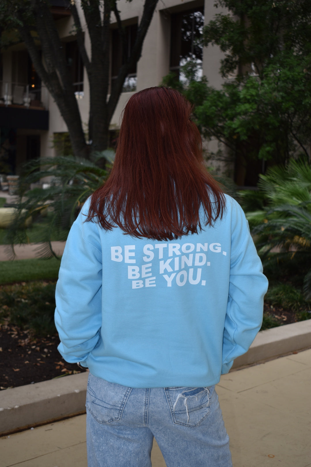 Dr. Betsy Grunch (Ladyspinedoc) wearing the light blue Be You sweatshirt showing "Be Strong. Be Kind. Be You." across the back.