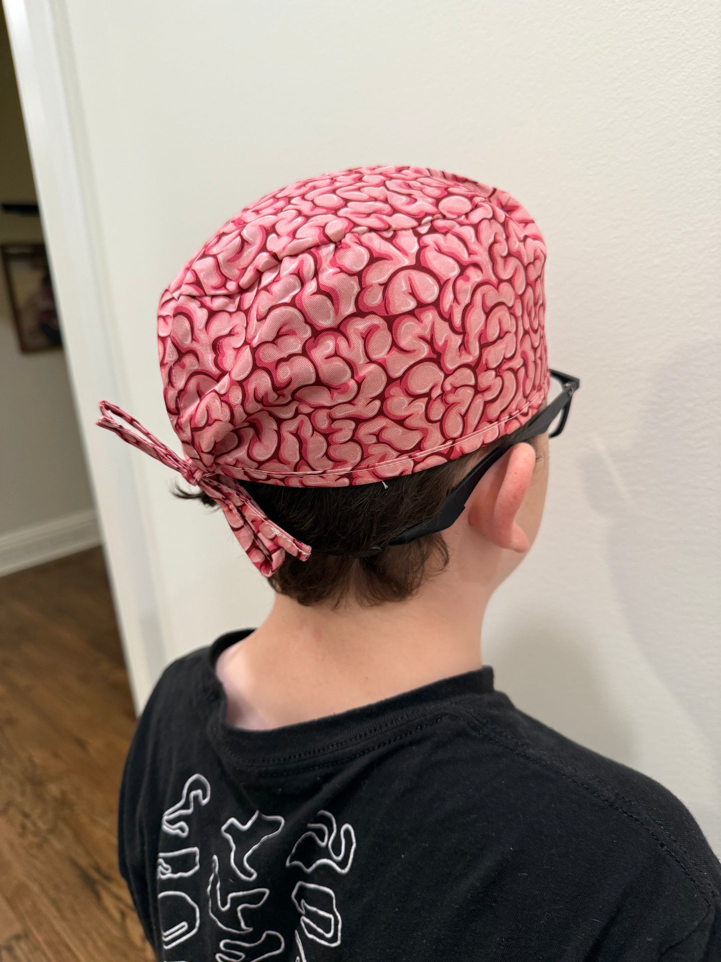 Back view of a youth wearing the tie-back (short hair) version of the Cortex Cap - Pink Scrub Hat with Brain Design