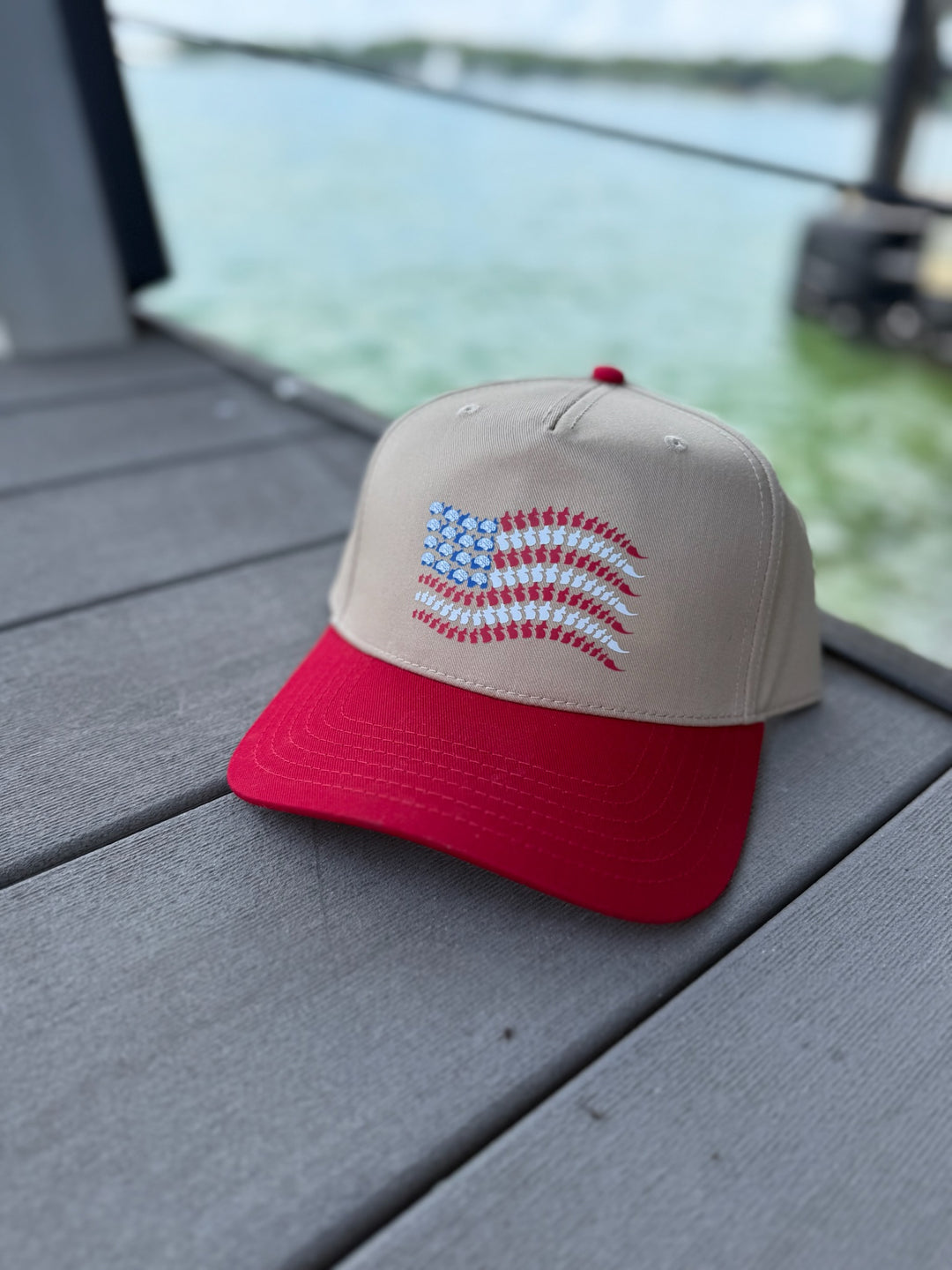 Neuro-themed red and tan snapback hat on wooden dock with lake background.