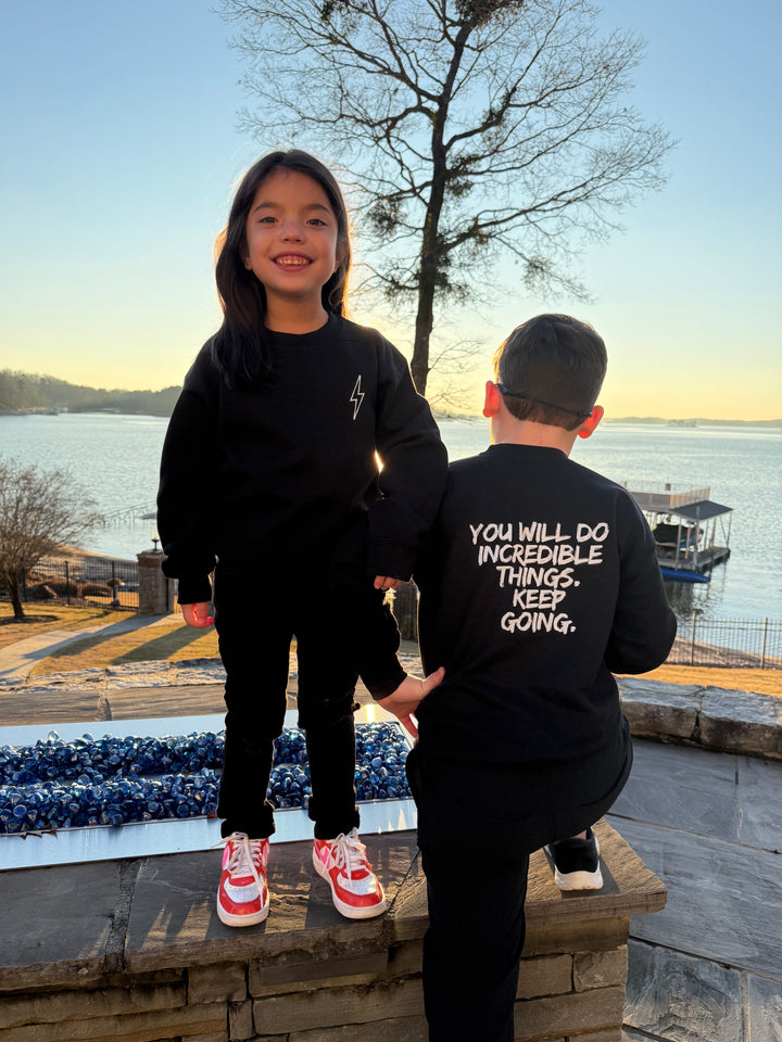 Girl facing front and boy facing back showing off the front and back views of the Incredible Youth Crewneck Sweatshirts.