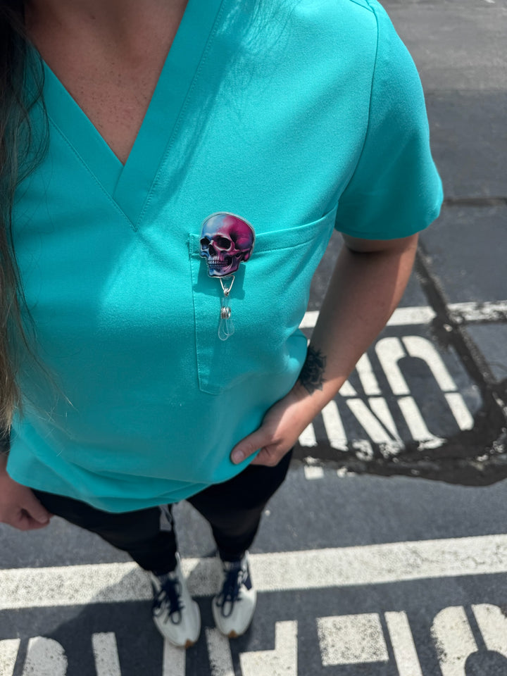 Super Skull Badge Reel - Retractable with Alligator Clip and Colorful Skull Design clipped on front pocket of woman's scrubs