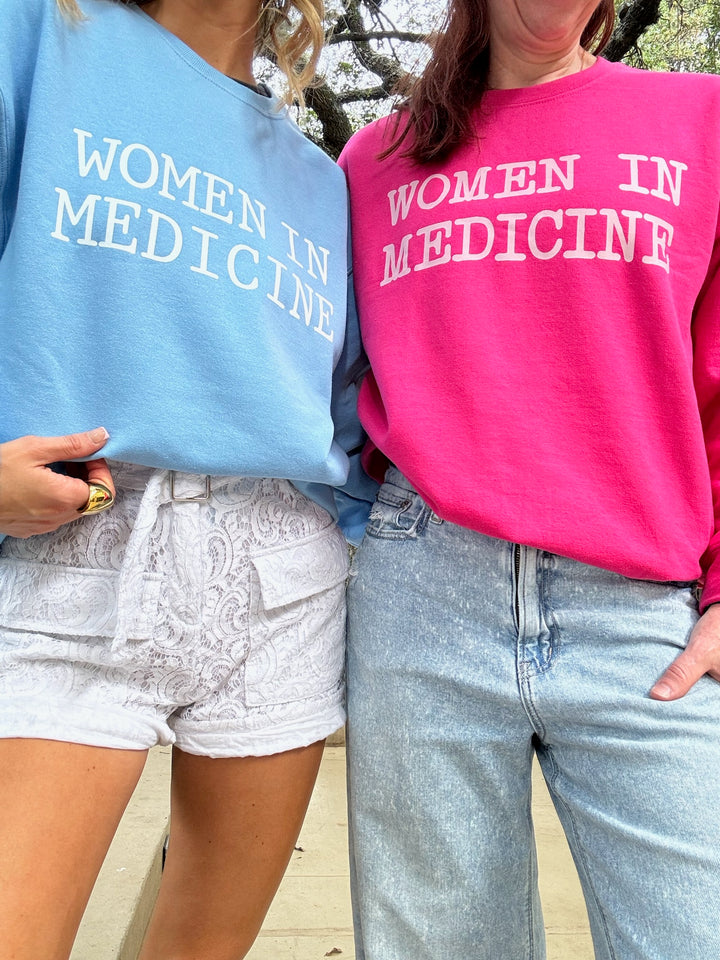 Women wearing light blue and hot pink Ladyspinedoc Women in Medicine sweatshirts