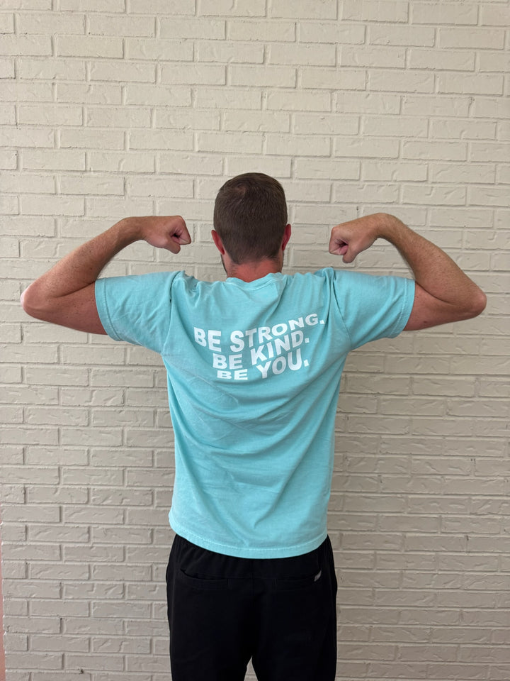 Back of male model doing a arm muscle stance and wearing the BE YOU Tee Shirt, showing the BE STRONG. BE KIND. BE YOU. motto on the back.
