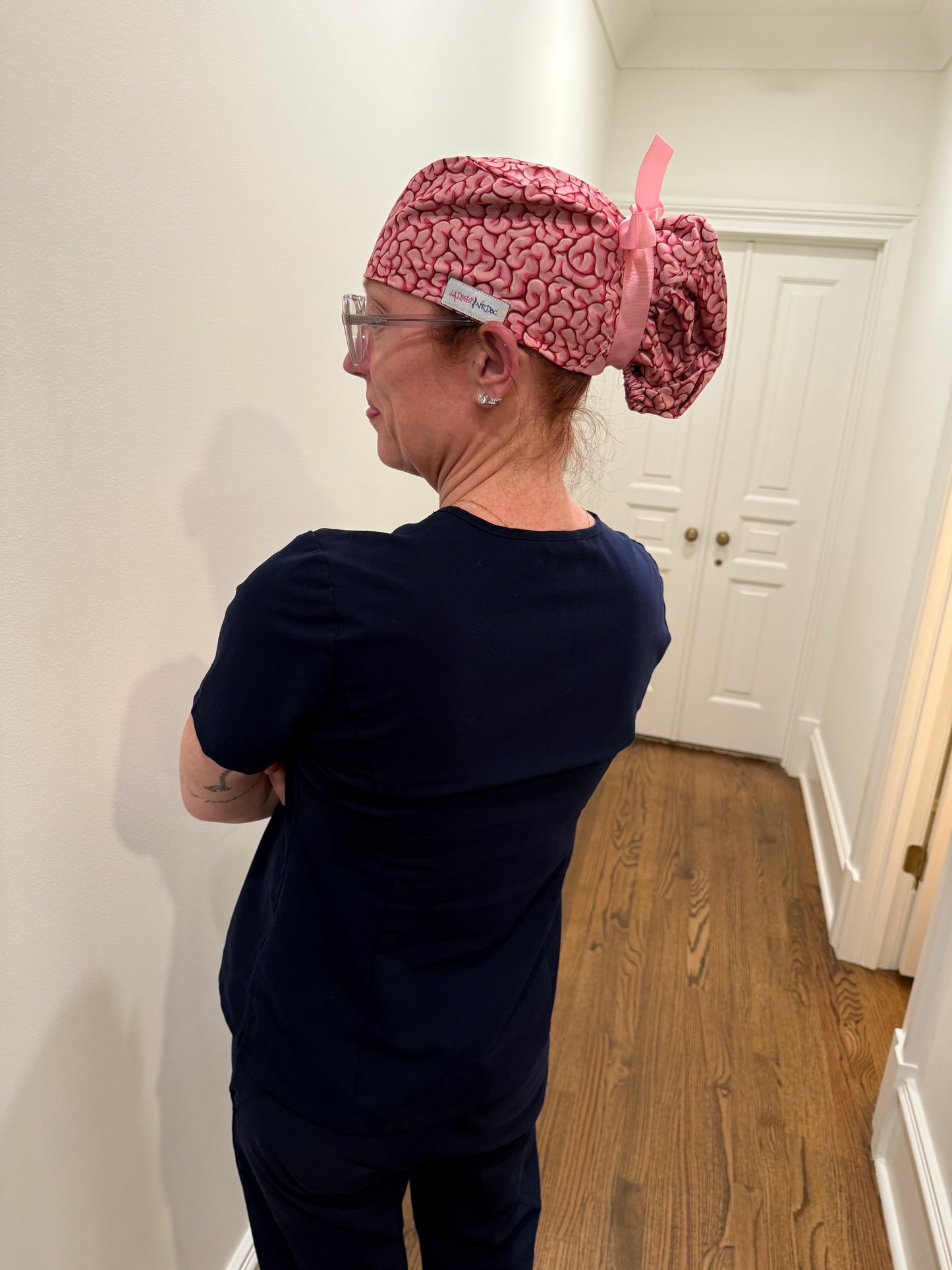 Side view of Ladyspinedoc wearing the Ponytail (long hair) version of her pink Cortex Scrub Hat with brain design