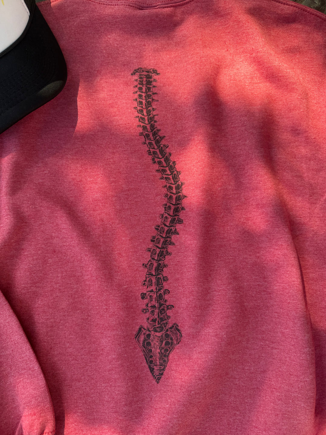Close up view of the curved spine design on the back of the red Bent Not Broken Scoliosis Crewneck Sweatshirt.