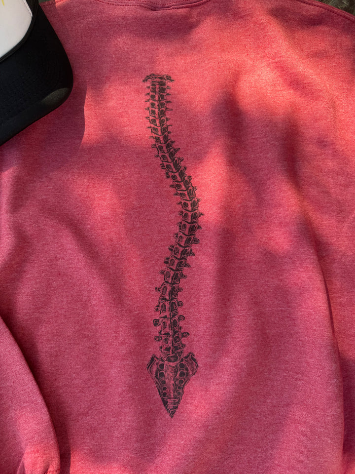 Close up view of the curved spine design on the back of the red Bent Not Broken Scoliosis Crewneck Sweatshirt.