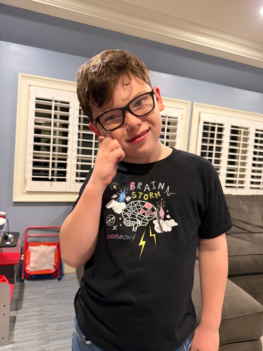 Youth model wearing the Ladyspinedoc x The Neuron Family - Youth Brain Storm Tee Shirt in Black