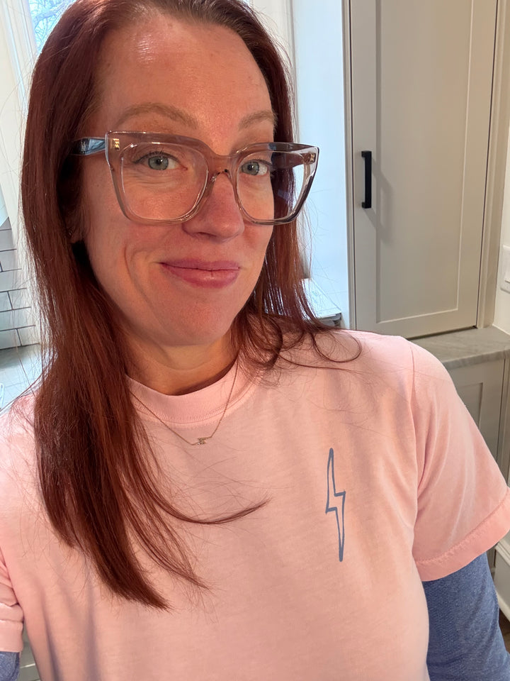 Close up of Dr. Betsy Grunch (Ladyspinedoc) wearing the light pink lumbar puncture tee shirt with lightning bolt on upper left chest.