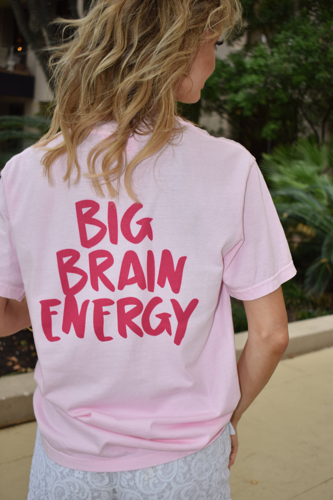 Back view of the Big Brain Energy tee on a model showing hot pink “BIG BRAIN ENERGY” text.
