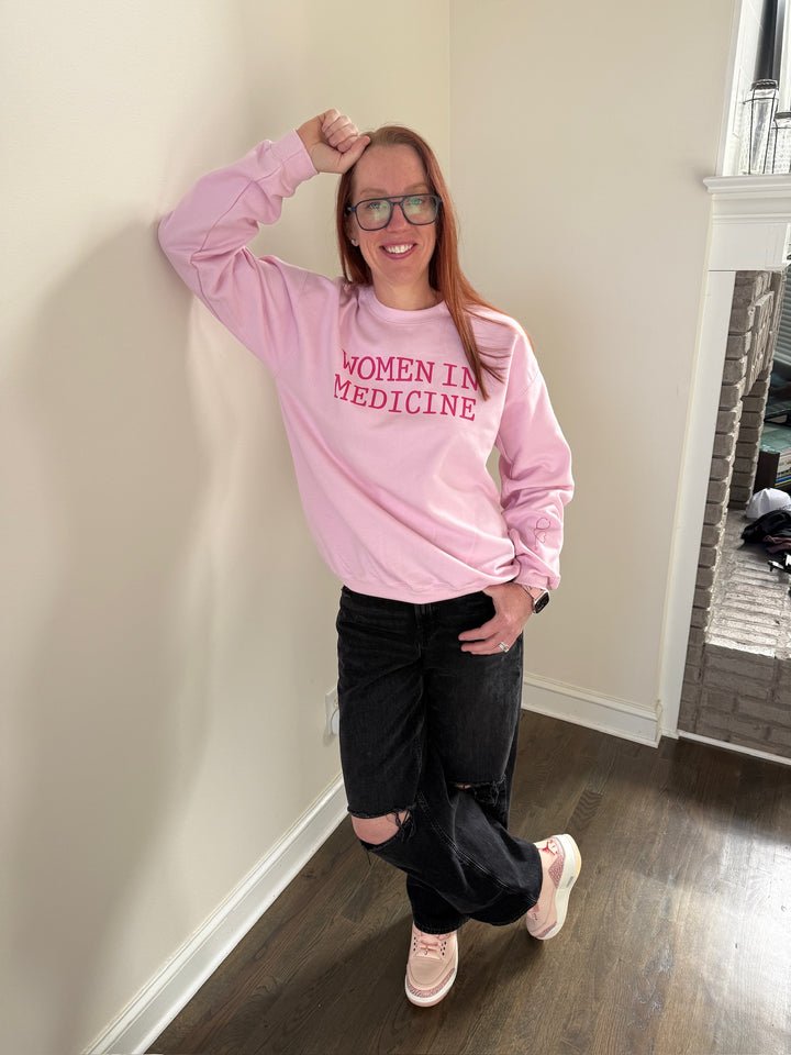 Dr. Betsy Grunch - Ladyspinedoc wearing light pink crewneck sweatshirt with bold "WOMEN IN MEDICINE" text across the chest, modeled for a relaxed fit.