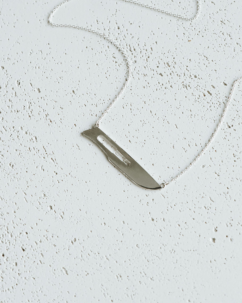 Flat lay of Sterling Silver 10 Blade Scalpel Pendant Necklace