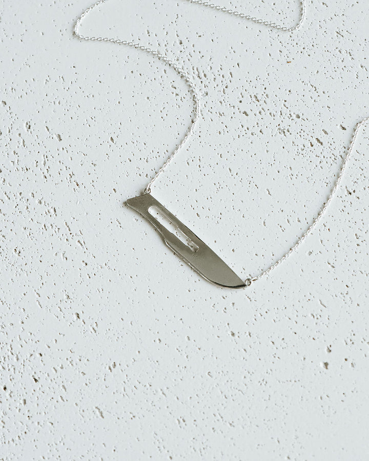 Flat lay of Sterling Silver 10 Blade Scalpel Pendant Necklace