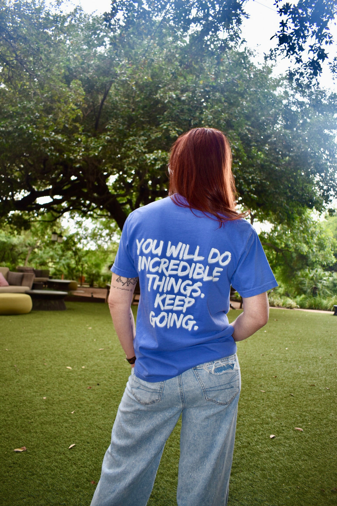 Ladyspinedoc showing the back of the tee with bold white text: “YOU WILL DO INCREDIBLE THINGS. KEEP GOING.”