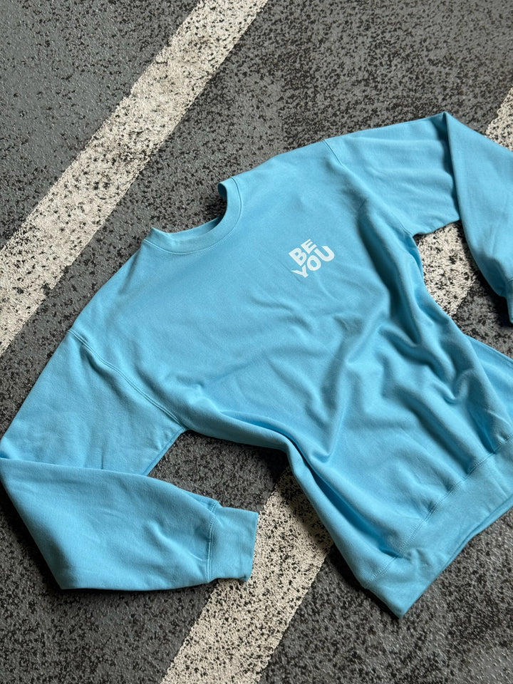 Flat lay of BE YOU Crewneck Sweatshirt in Light Blue on pavement