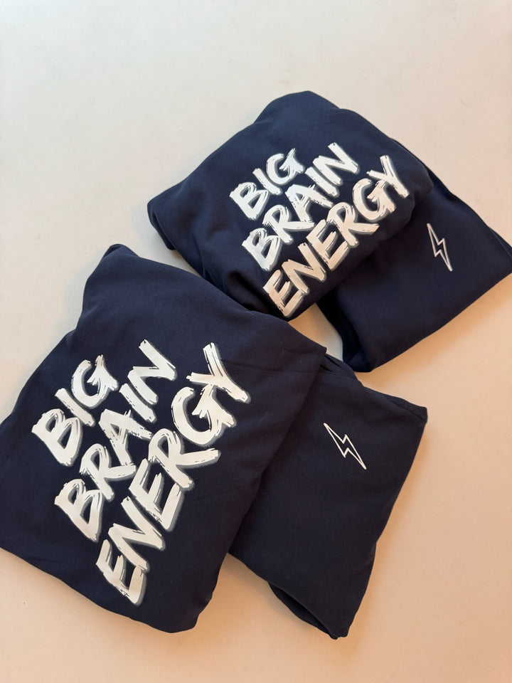 Adult and youth folded BIG BRAIN ENERGY hoodie on top of folded matching sweatpants.