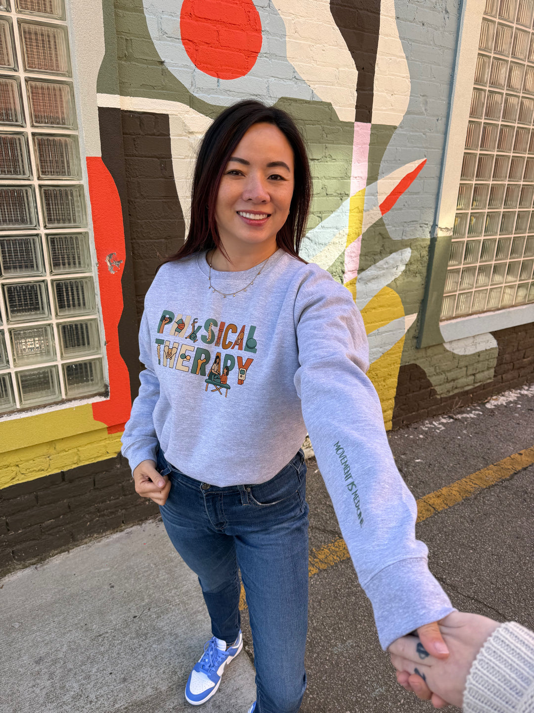 Person wearing a sweatshirt with 'Physical Therapy' on the front and 'Movement is Medicine" on the sleeve.