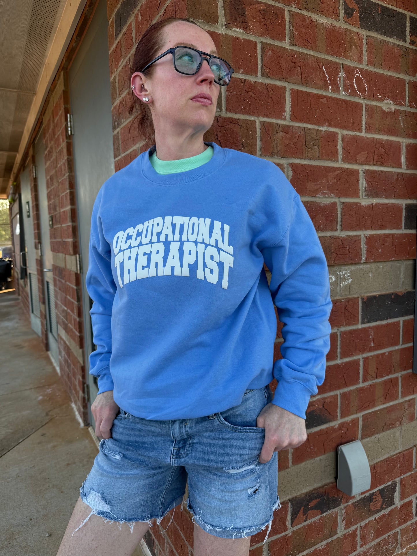 Dr. Betsy Grunch (Ladyspinedoc) modeling her blue Occupational Therapist sweatshirt.
