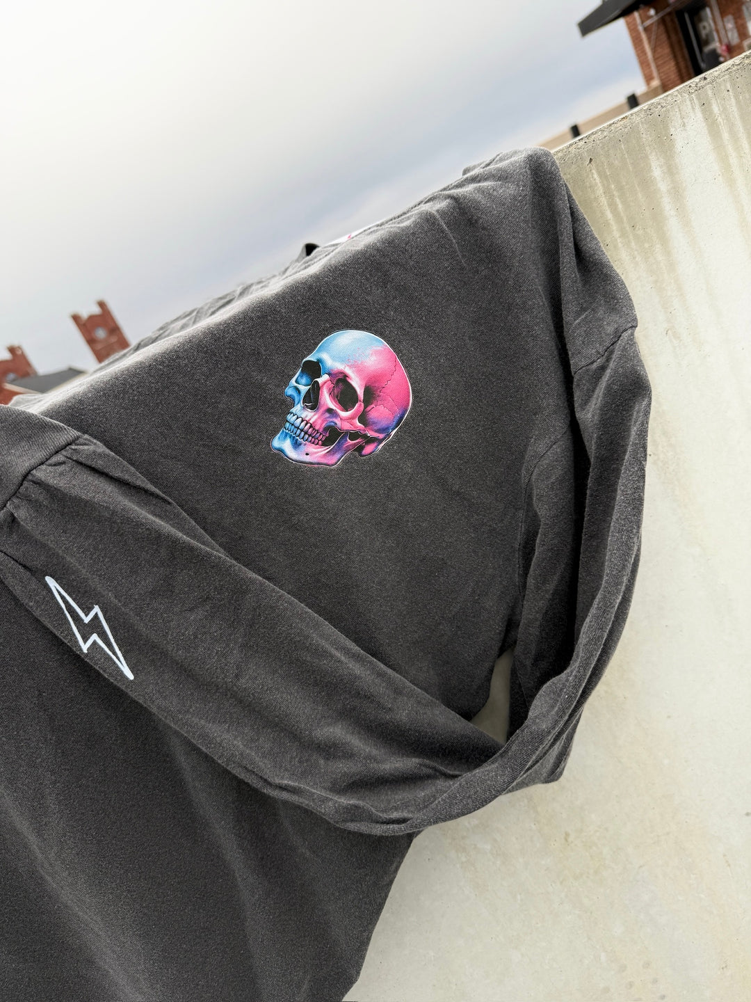 Skull Powers Long Sleeve Tee Shirt - Dark Gray with Skull and Lightning Bolt Designs on a wall, showing off the skull and bolt designs