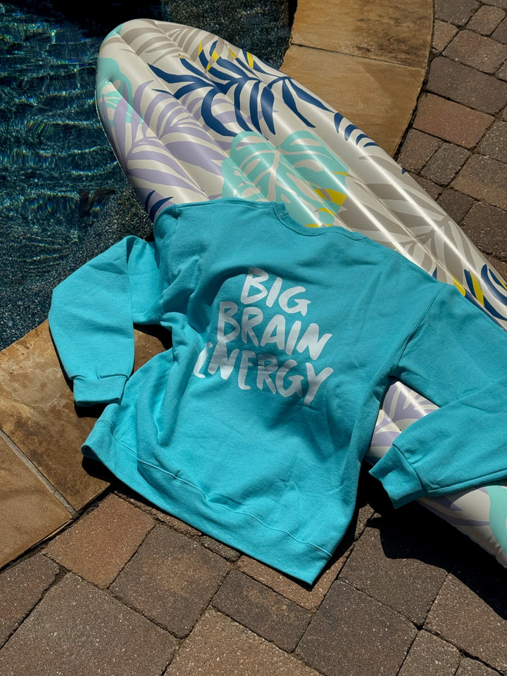 Turquoise hoodie with 'BIG BRAIN ENERGY' text on a poolside surface