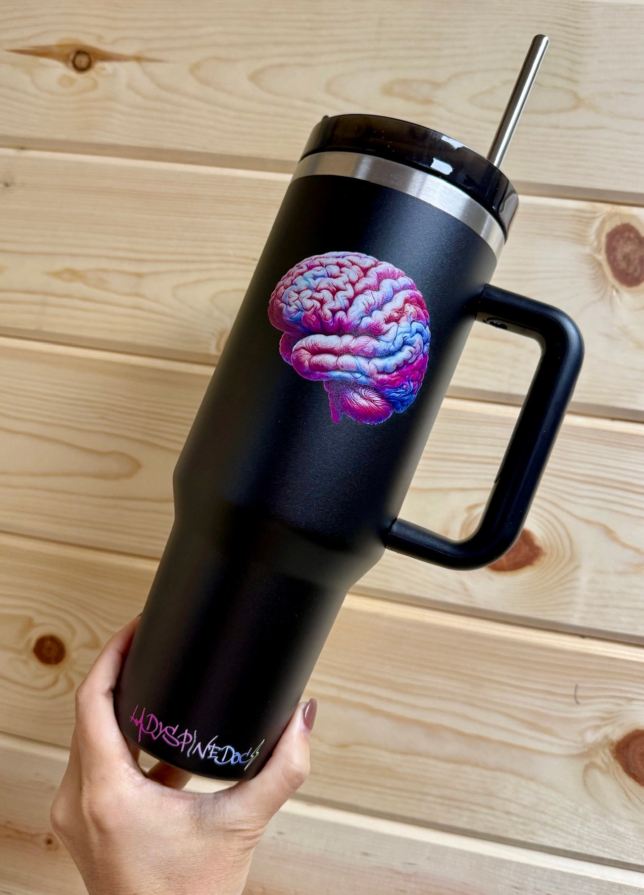 Hand holding the Big Brain Energy Cup to show scale and matte black finish with brain graphic