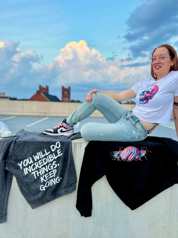 Ladyspinedoc sitting on concrete wall and wearing the Skull Style Cropped Tee – White Short Sleeve Crop Top with Skull Design
