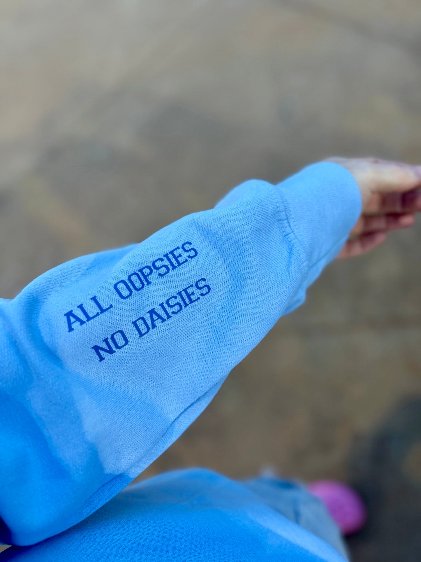“ALL OOPSIES NO DAISIES” on the left sleeve of light blue Nurse sweatshirt