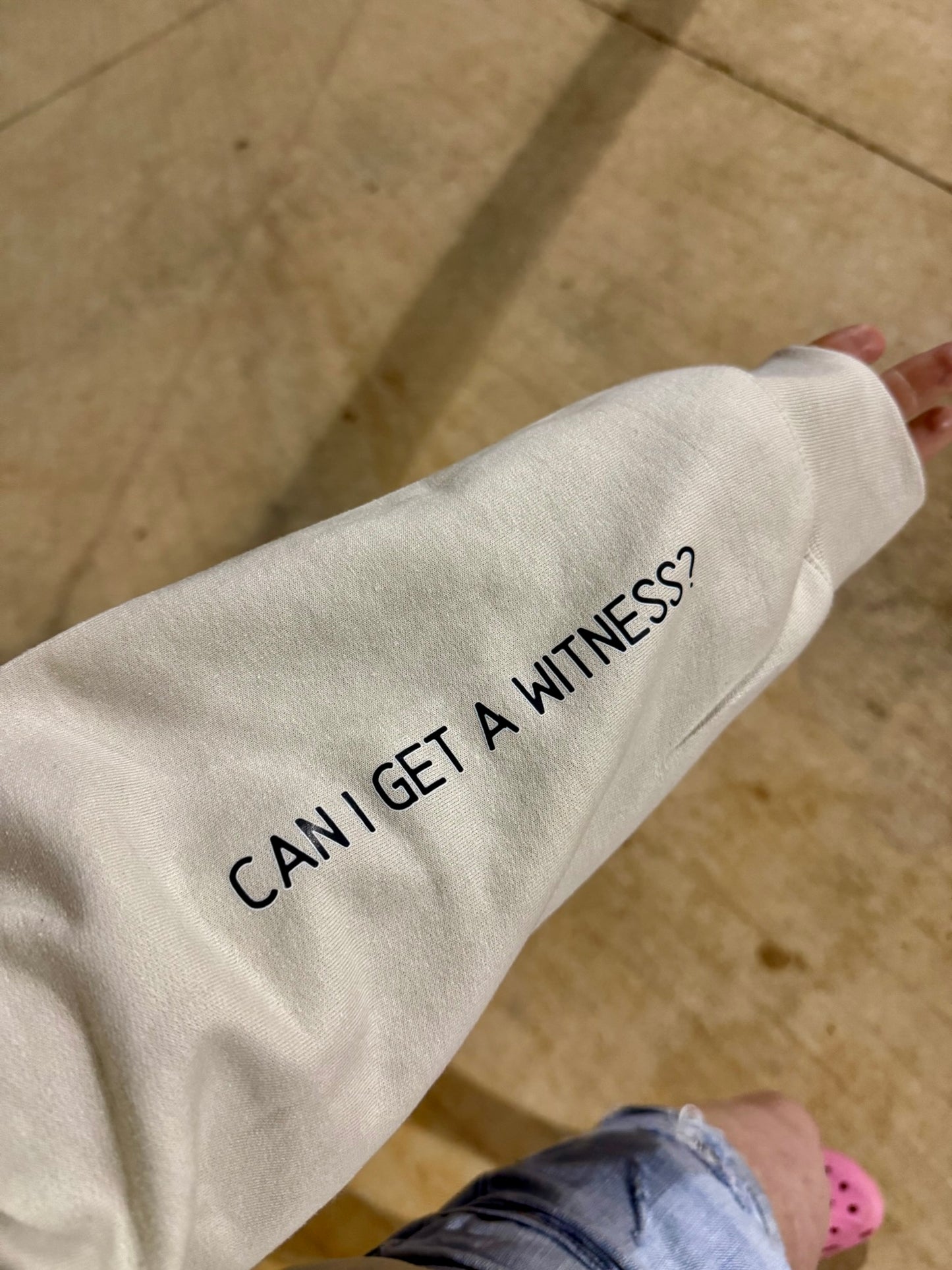 Sand-colored sweatshirt sleeve with black text that reads “CAN I GET A WITNESS?” for nurse humor
