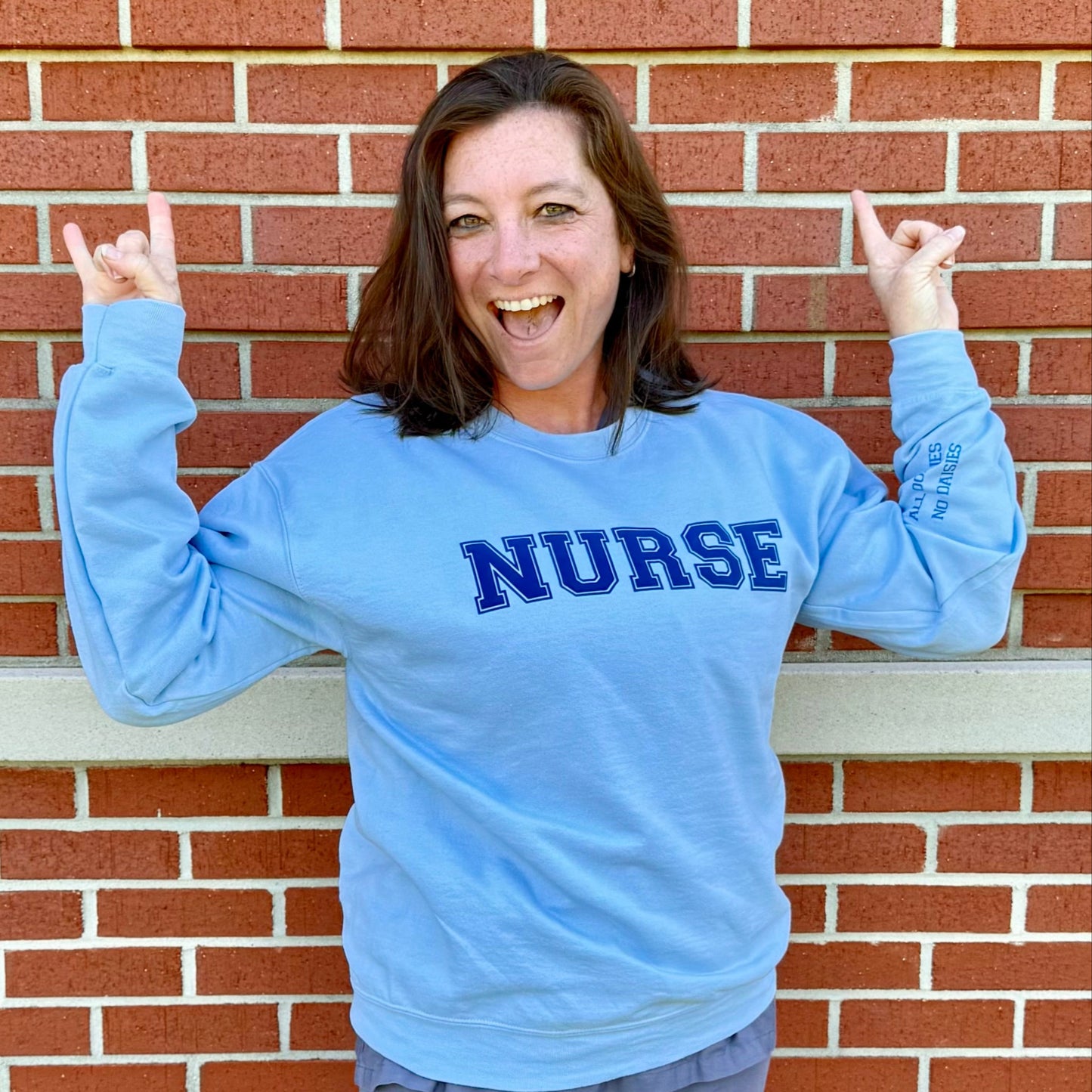 Dr. Betsy Grunch's nurse, Kandi Hulsey, wearing a size medium of the All Oopsies No Daisies Nurse Sweatshirt.