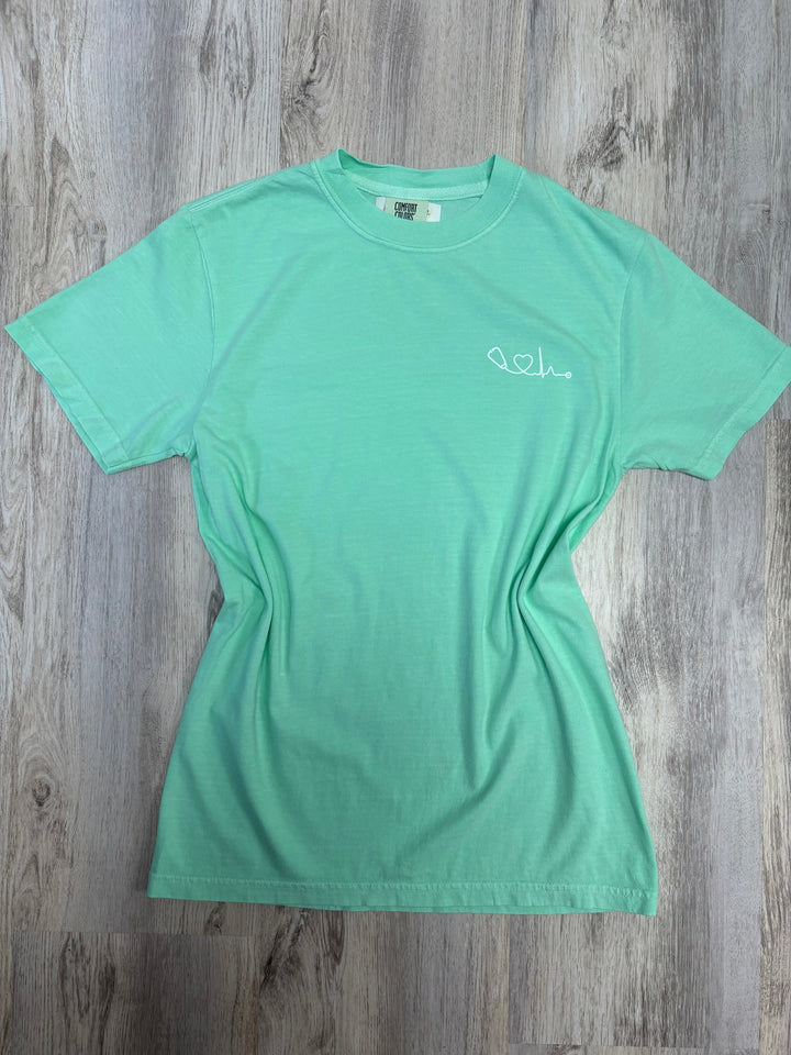 Front view of light green Heart of Medicine t-shirt featuring Dr. Beachgem’s stethoscope and heart waveform logo on the upper left chest.