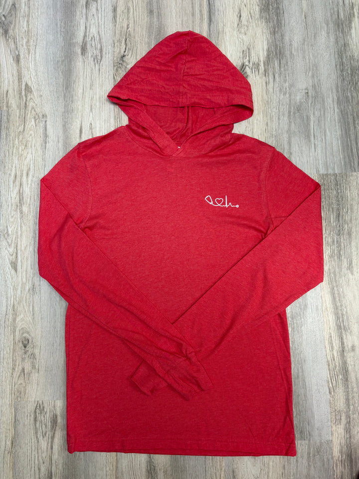 Flat lay of Heart of Medicine red long-sleeve hooded T-shirt with a white heart and stethoscope graphic on the chest, displayed on a wood floor — breathable medical-themed hoodie for nurses, doctors, and healthcare advocates.