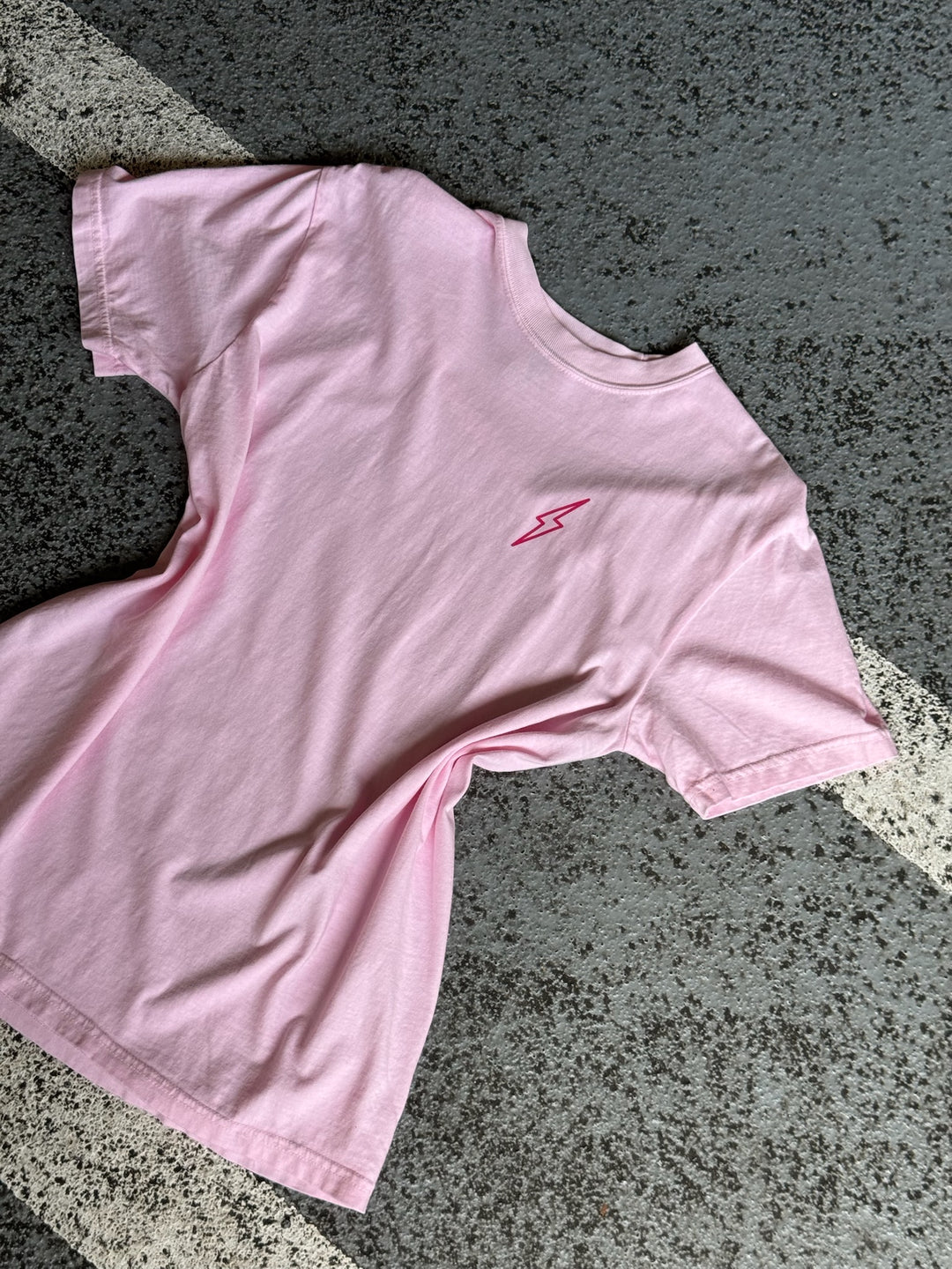 Flat lay of the front of the Big Brain Energy pink t-shirt showing a hot pink lightning bolt design.
