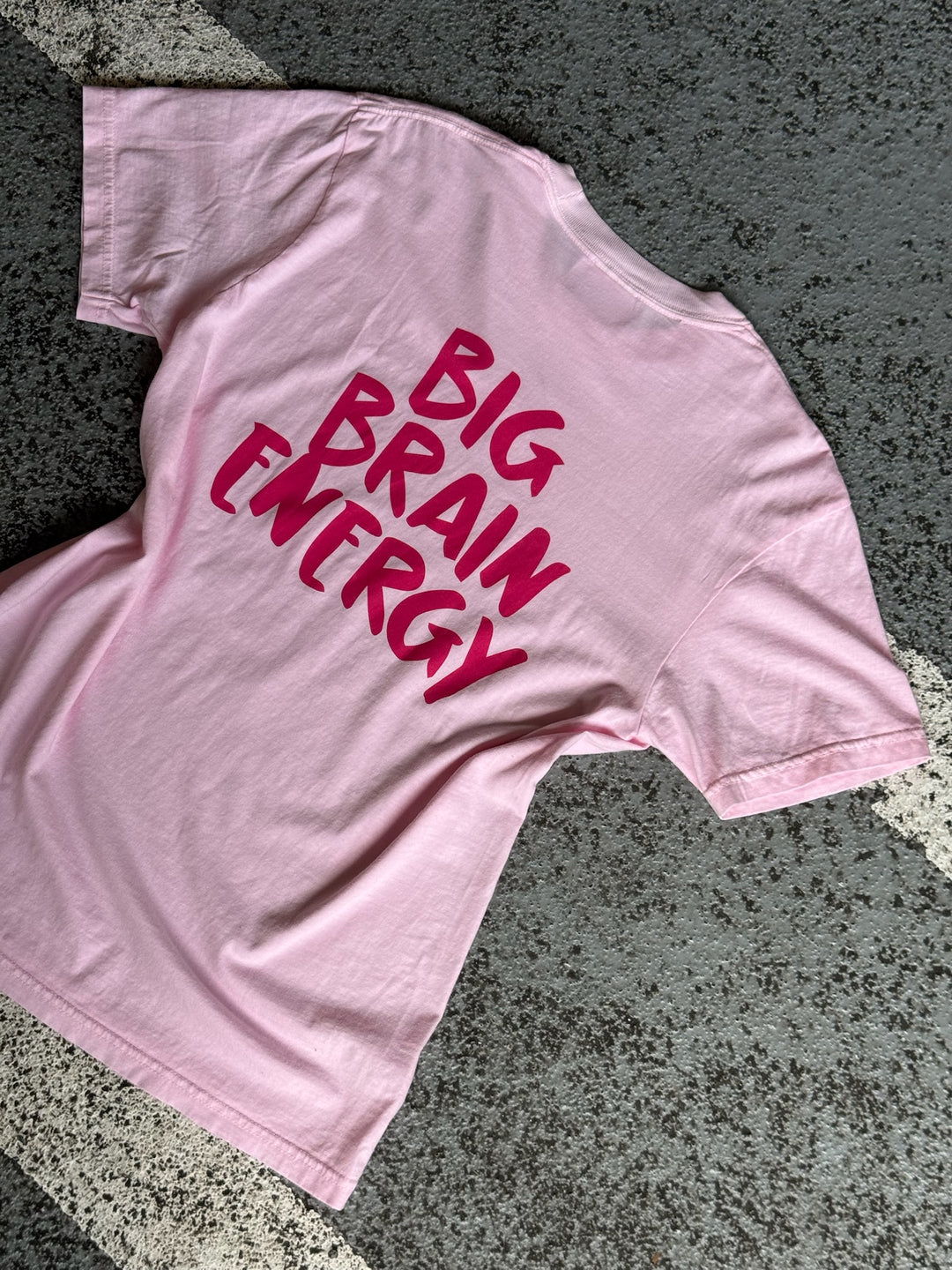 Flat lay of the back of the pink Big Brain Energy t-shirt with bold hot pink text.