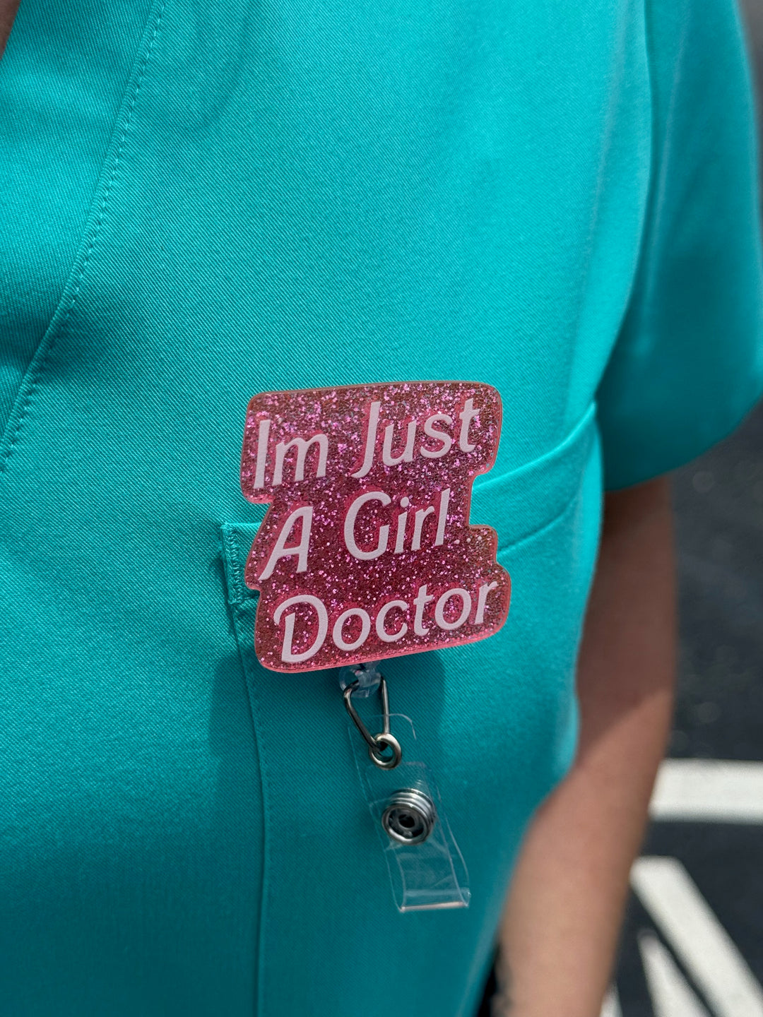 Ladyspinedoc x Dr. Daisy Collab: Pink "I'm Just A Girl Doctor" Badge Reel clipped on front pocket of scrubs
