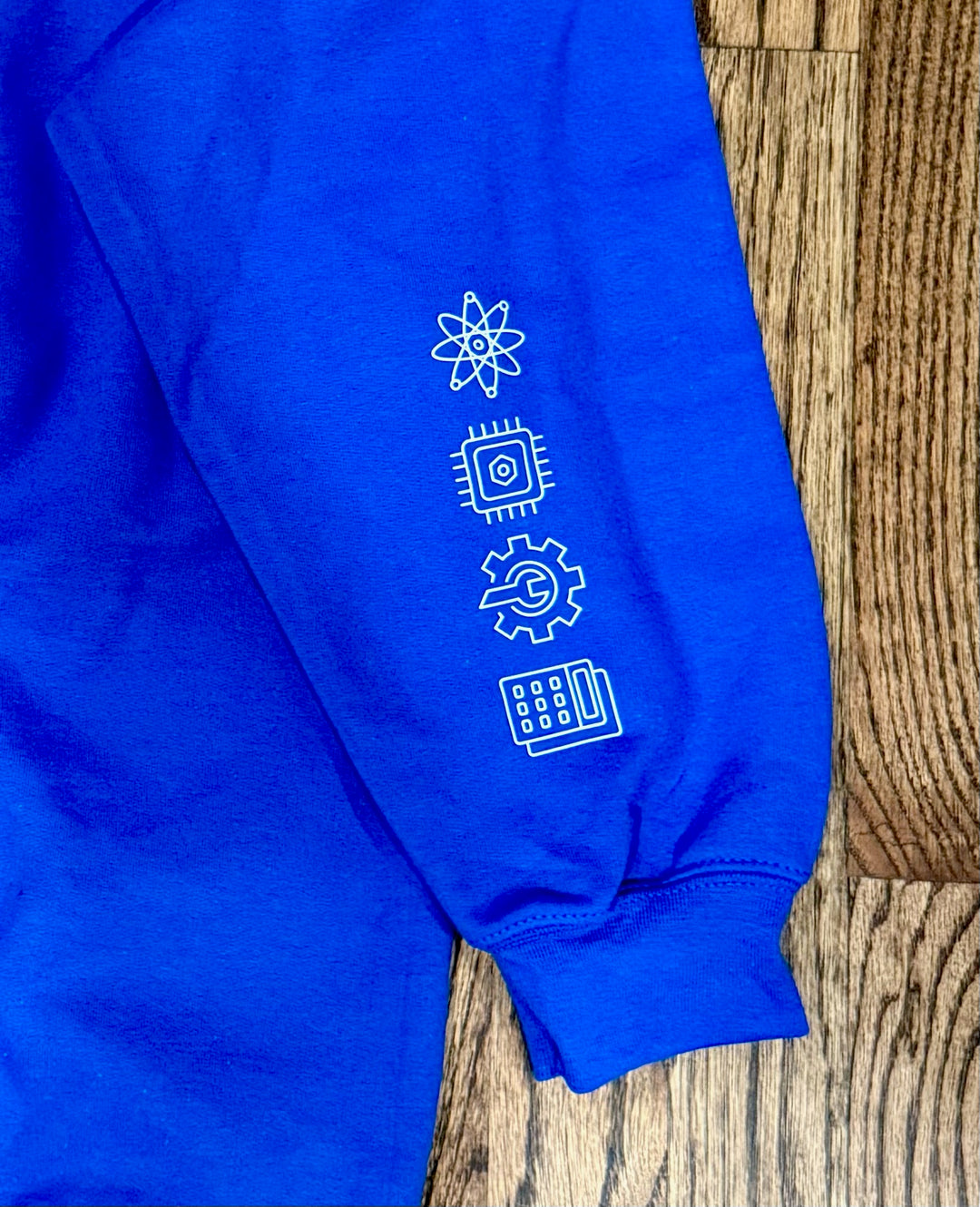 “Women in STEM” Sweatshirt showing close-up view of the STEM icons of Science, Technology, Engineering, and Mathematics displayed on the left sleeve.