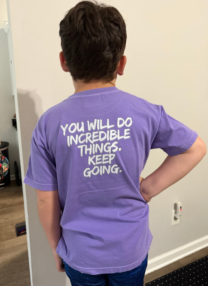 Back of boy wearing the violet  Incredible Youth Tee, showing the message, "You will do incredible things. Keep Going."