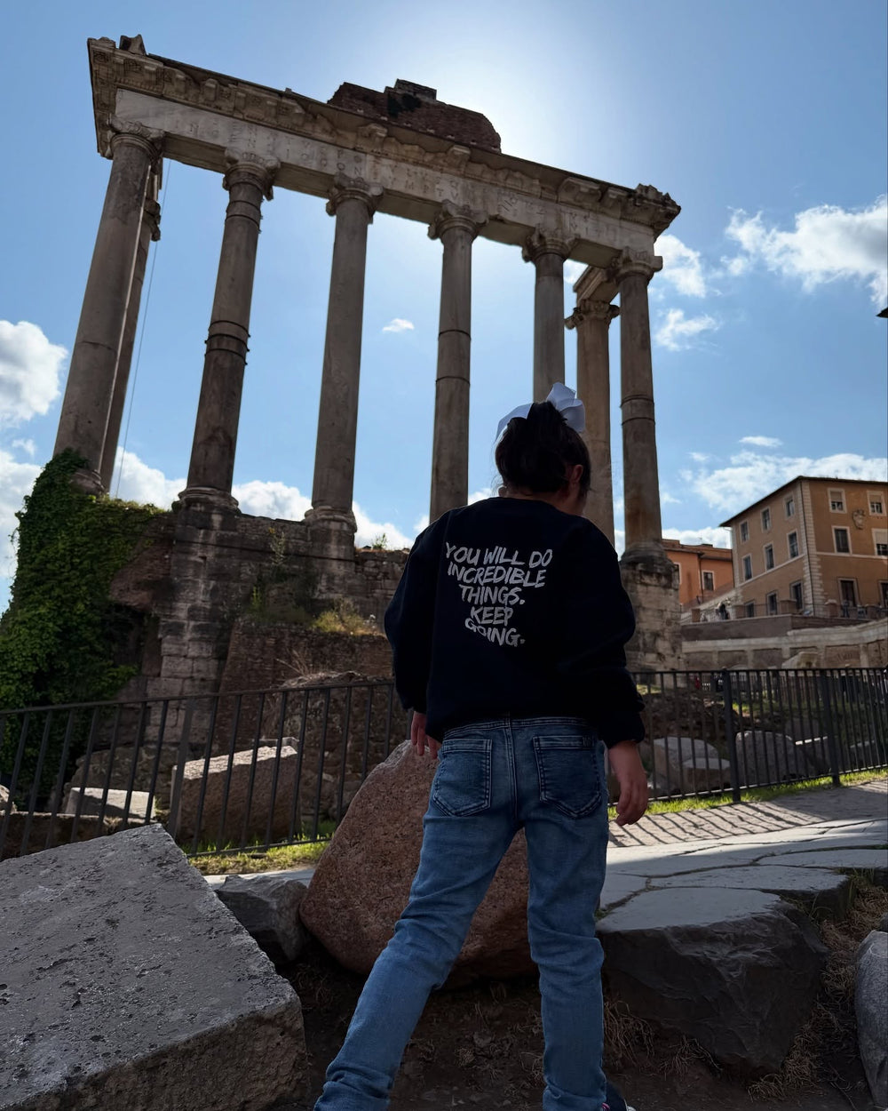 Back of young girl in Rome, Italy wearing the Kids Incredible Sweatshirt with "YOU WILL DO INCREDIBLE THINGS. KEEP GOING."  motto.