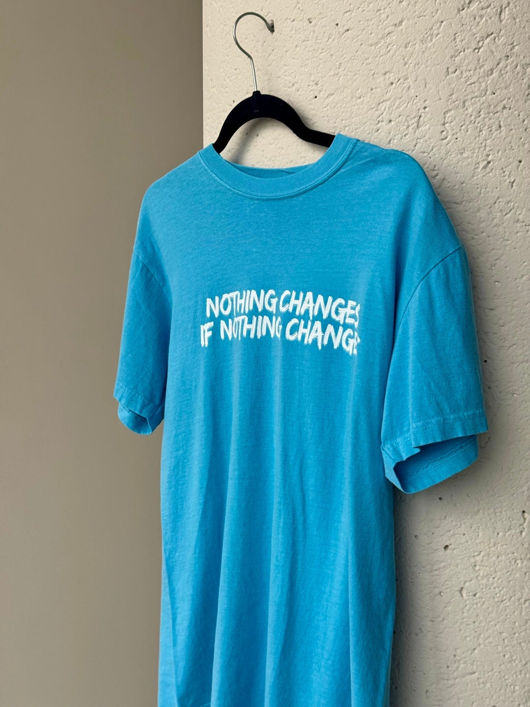 Blue tee shirt with "Nothing changes if nothing changes" on the front.