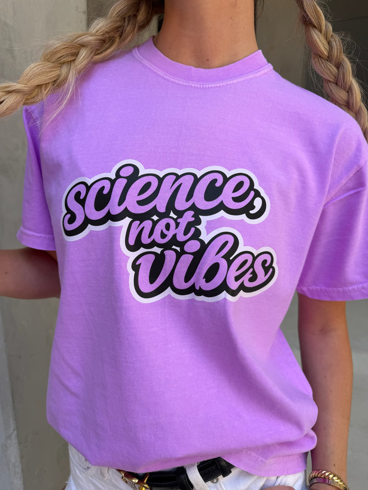 Person wearing a purple t-shirt with 'science, not vibes' text.