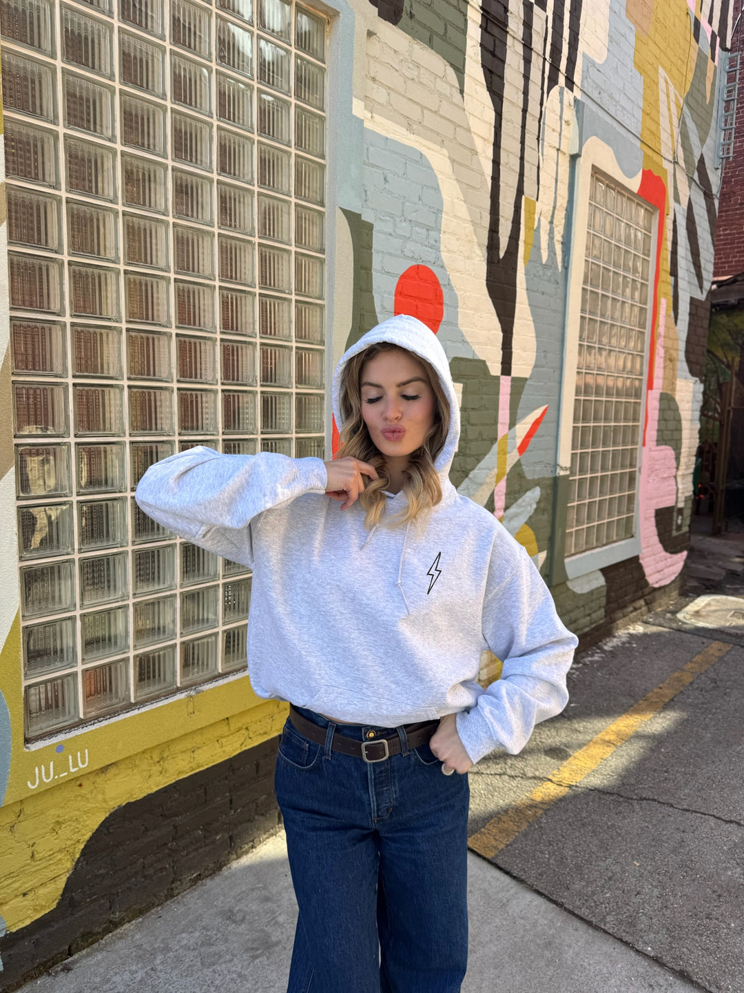Person wearing The Cerebrospinal Hoodie - Light Gray Anatomical Brain and Spine Graphic Sweatshirt in front of a colorful mural.