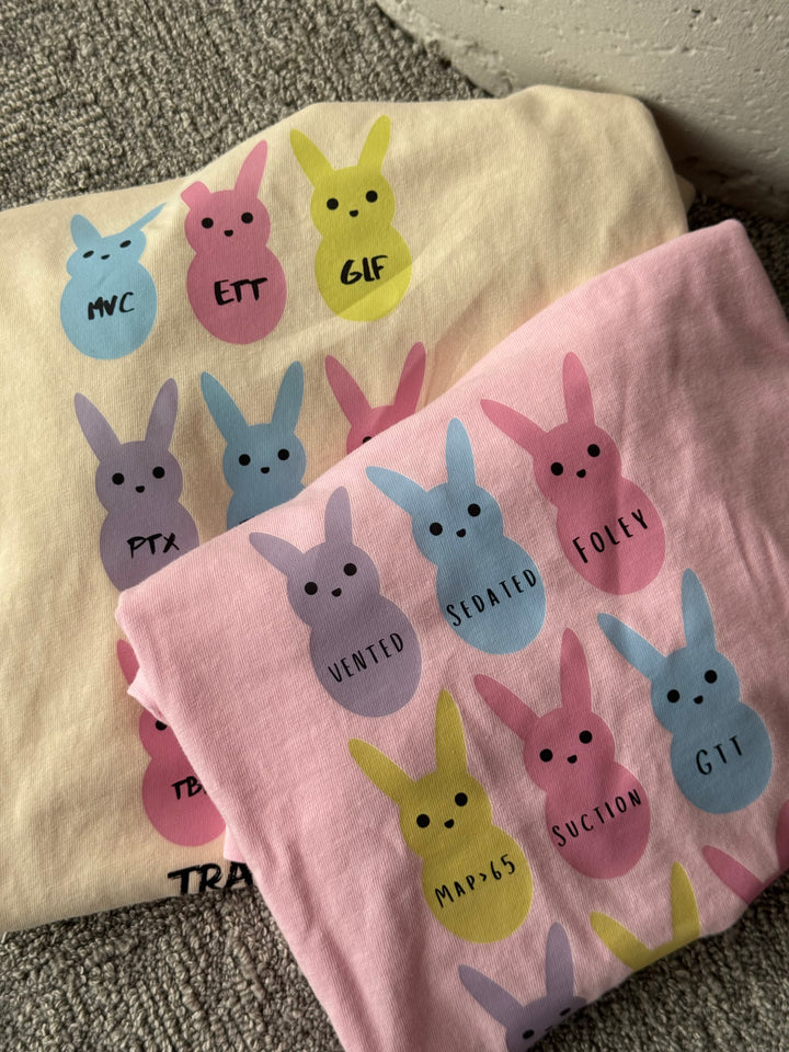 Folded  Trauma Squad and ICU Squad tee shirts with pastel bunny designs.