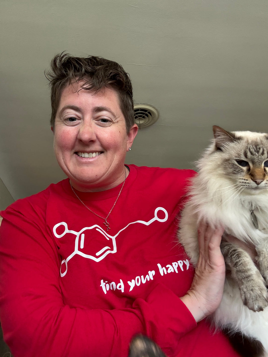 Dr. Beachgem holding a cat and wearing a white dopamine molecule printed on a red sweatshirt, representing the brain’s feel-good neurotransmitter.
