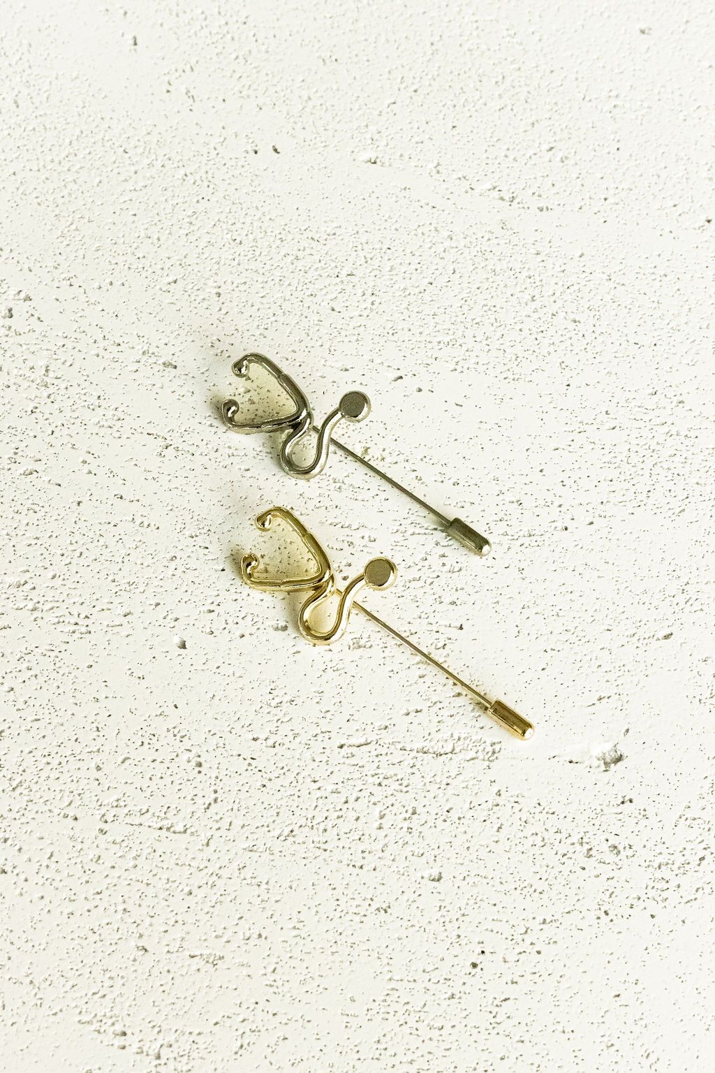 Gold and Silver Stethoscope Jacket Lapel Pins side by side on a white surface.