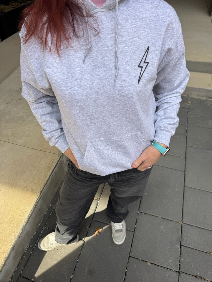 Dr. Betsy Grunch - Ladyspinedoc wearing the BIG BRAIN ENERGY light gray hoodie with the hood up, showcasing the brain design on the left side of the hood.
