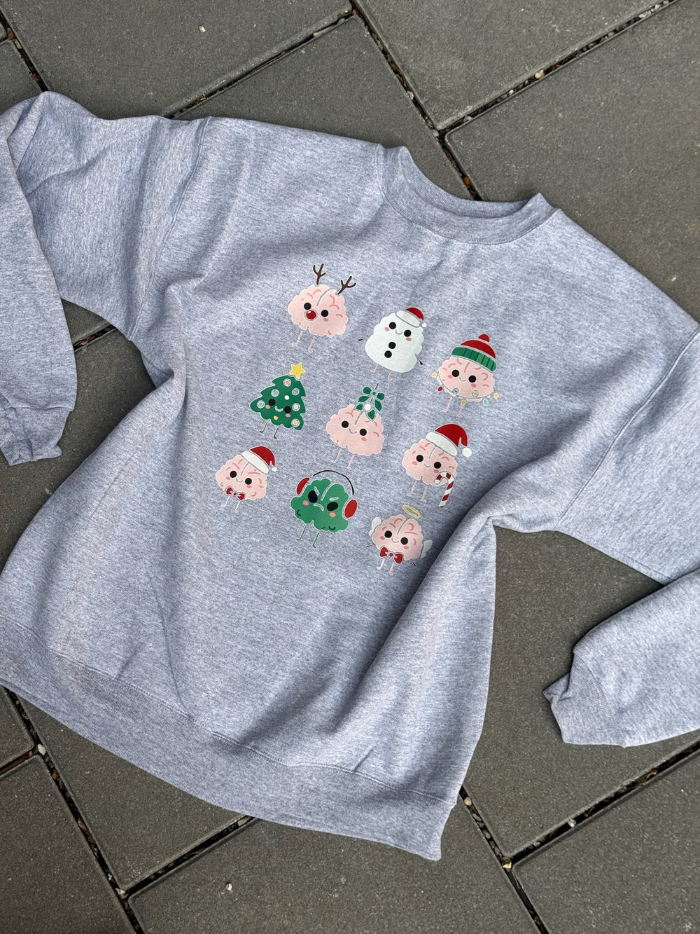 Gray sweatshirt with Christmas brain cartoon character designs on a tiled floor