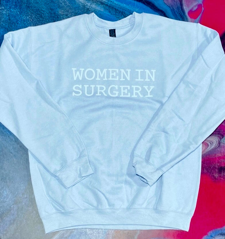 Light blue sweatshirt with 'WOMEN IN SURGERY' text on a colorful background