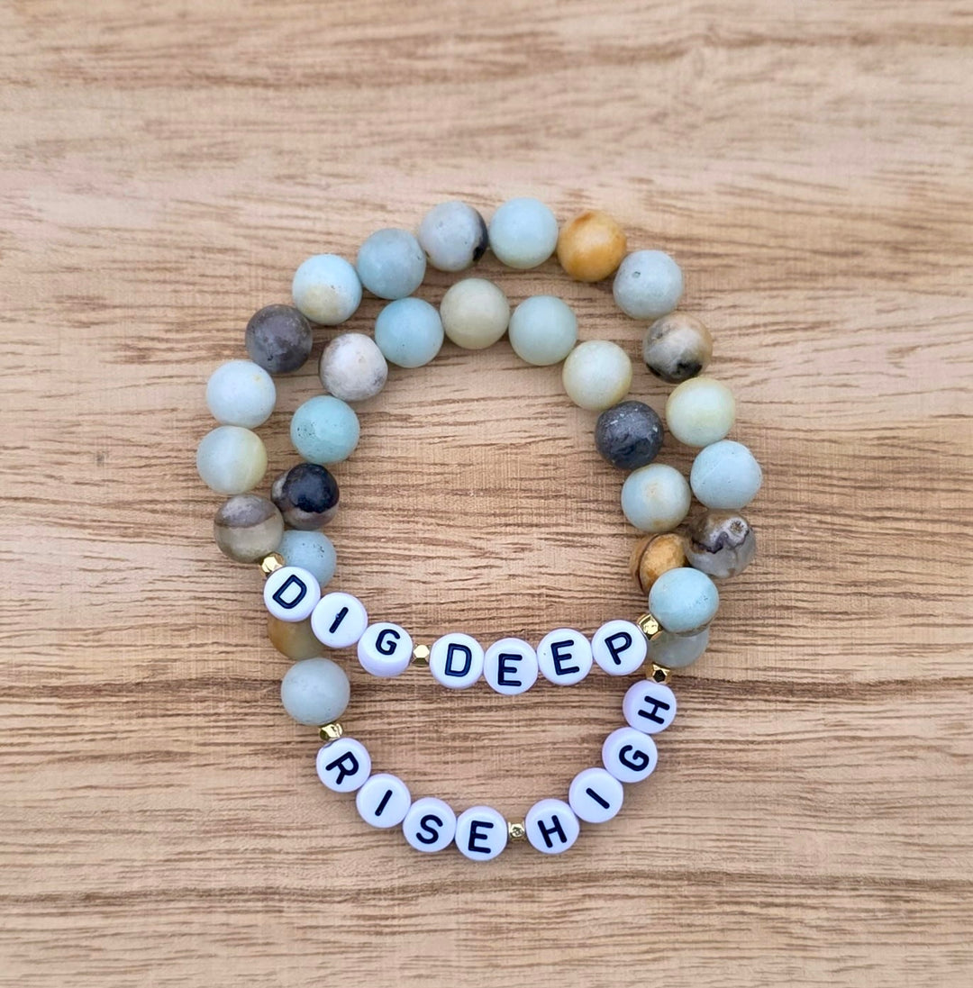 Ladyspinedoc x Dr. Potter: Dig Deep. Rise High beaded bracelets on a wooden surface