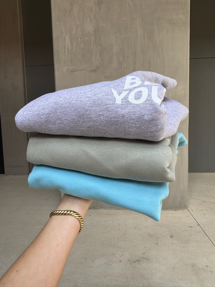Crewnecks stacked with the font in bold “BE YOU” on the front. 